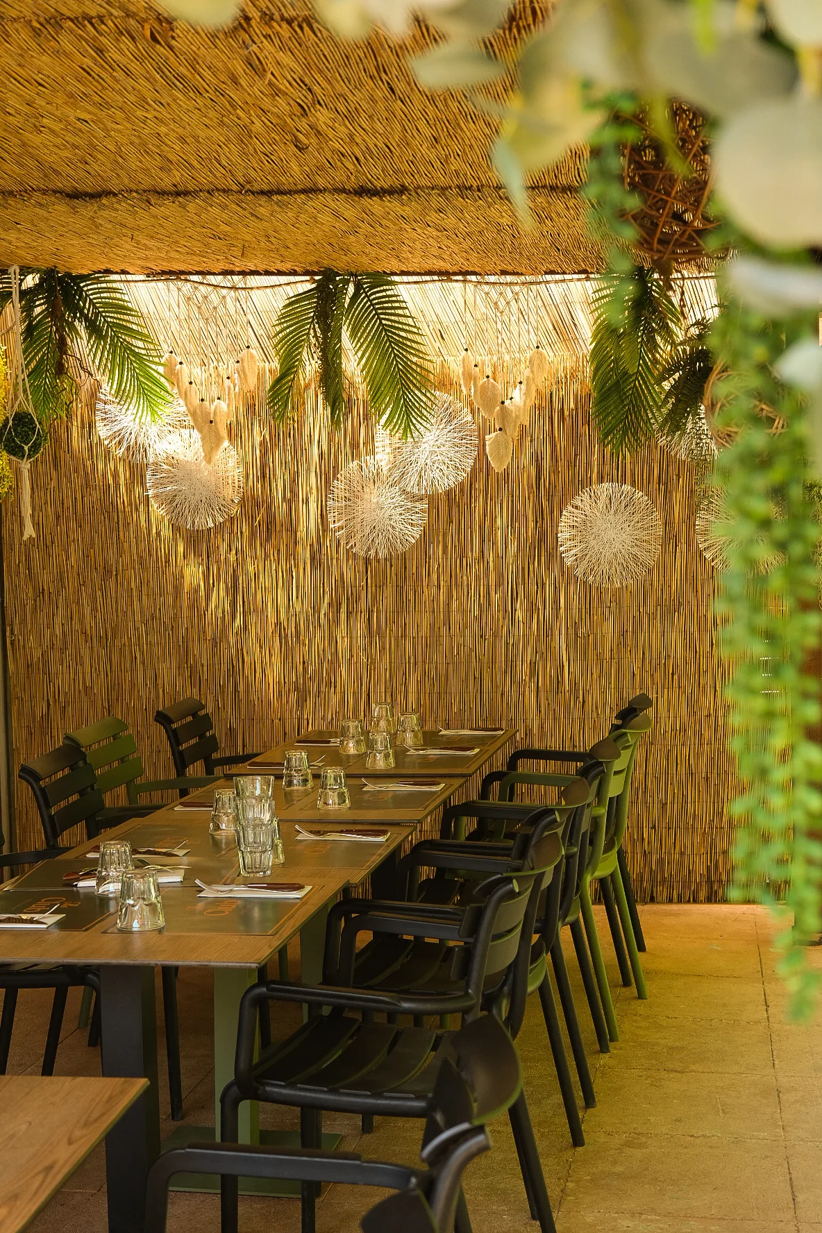 La partie couverte de la terrasse, au plafond de canisses, tables dressées