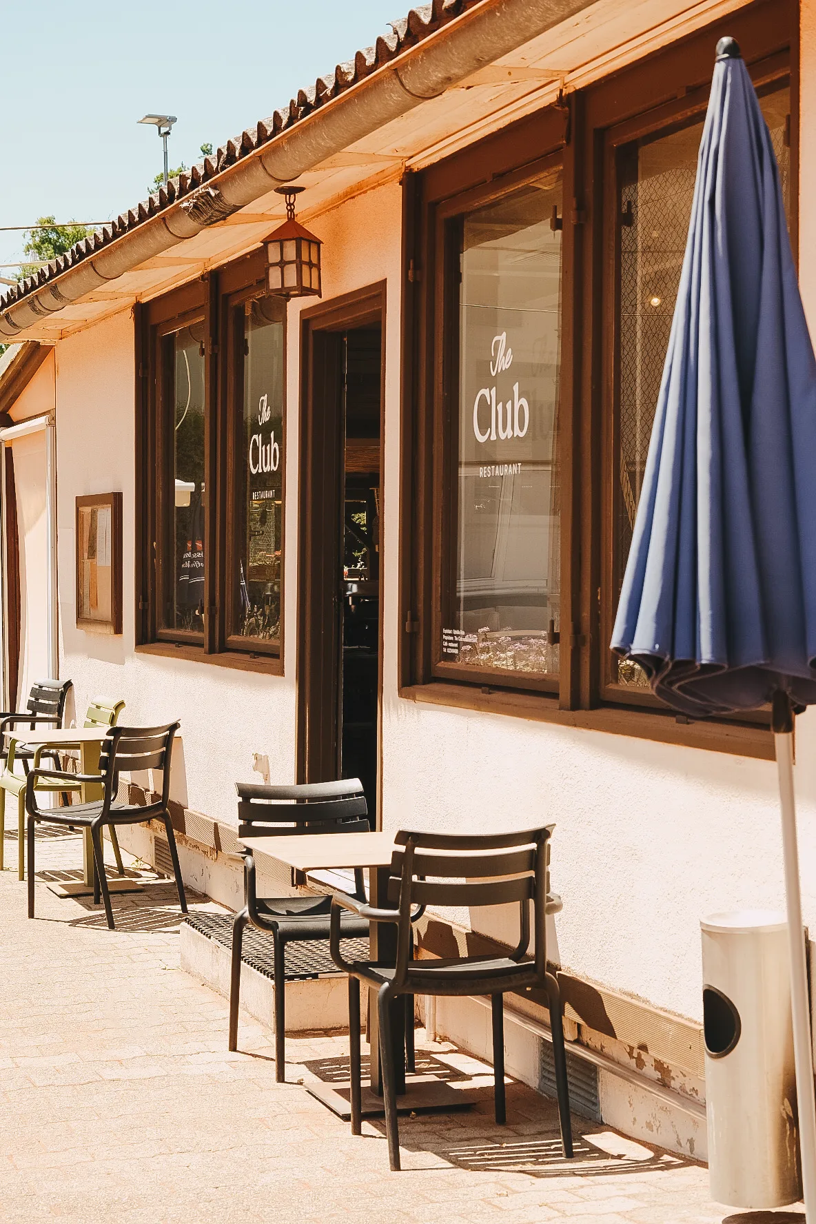 La façade de The Club Restaurant et ses tables en terrasse, au soleil