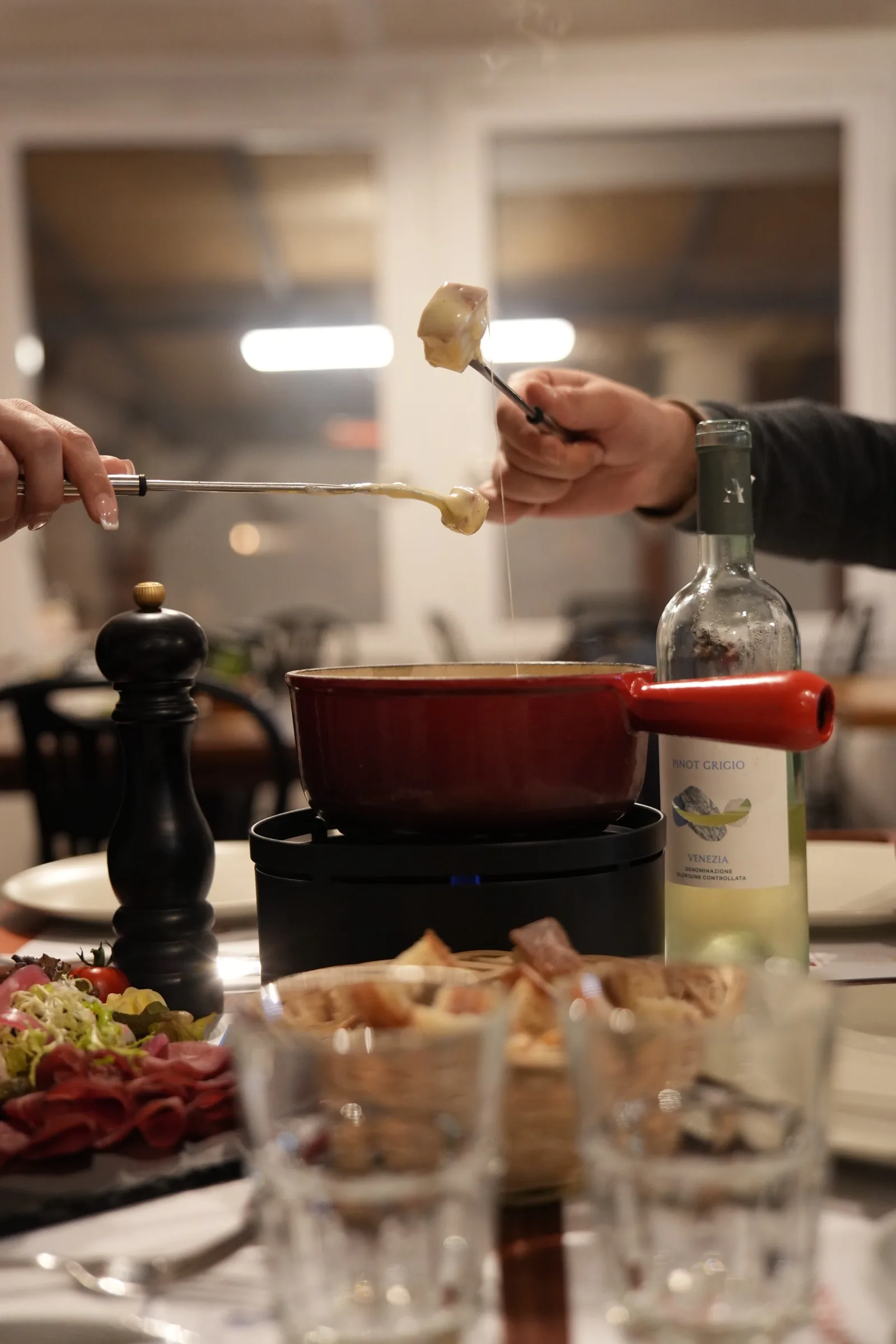 Des fourchettes à fondue plongées dans le caquelon, entre amis