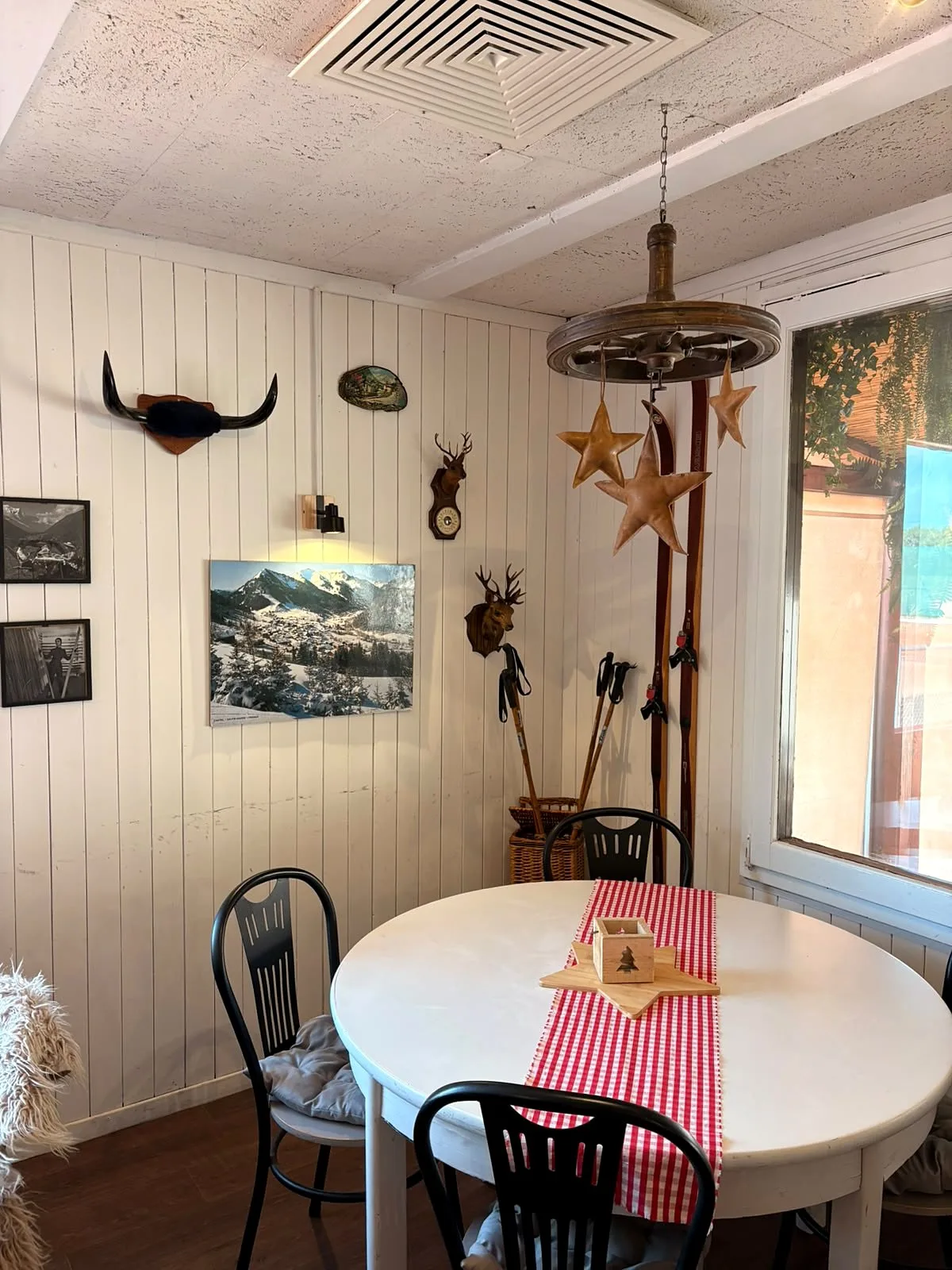Corner of the dining room with a round table, vintage skis, trophies and wooden stars