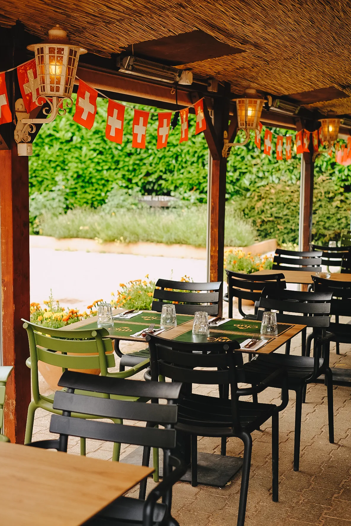 La partie couverte de la terrasse, ses tables et ses fanions rouges et blancs, côté jardin