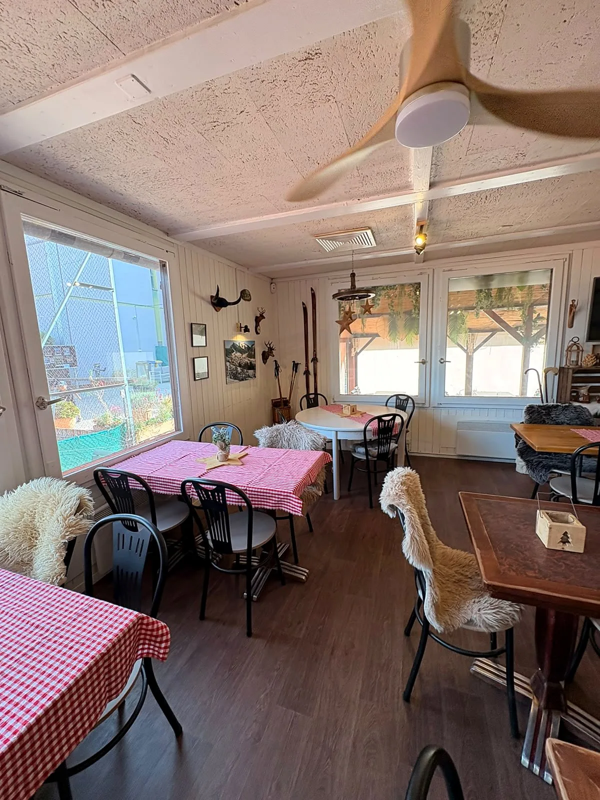 La salle de The Club Restaurant au décor de chalet : nappes à carreaux, peaux de mouton, skis et trophées